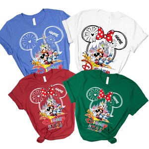 May include: Four short-sleeved t-shirts in blue, white, red, and green. Each shirt features a graphic of a castle, fireworks, and Disney characters inside a Mickey Mouse outline. The text "NAME" and "DISNEY 2020" are printed on the designs.