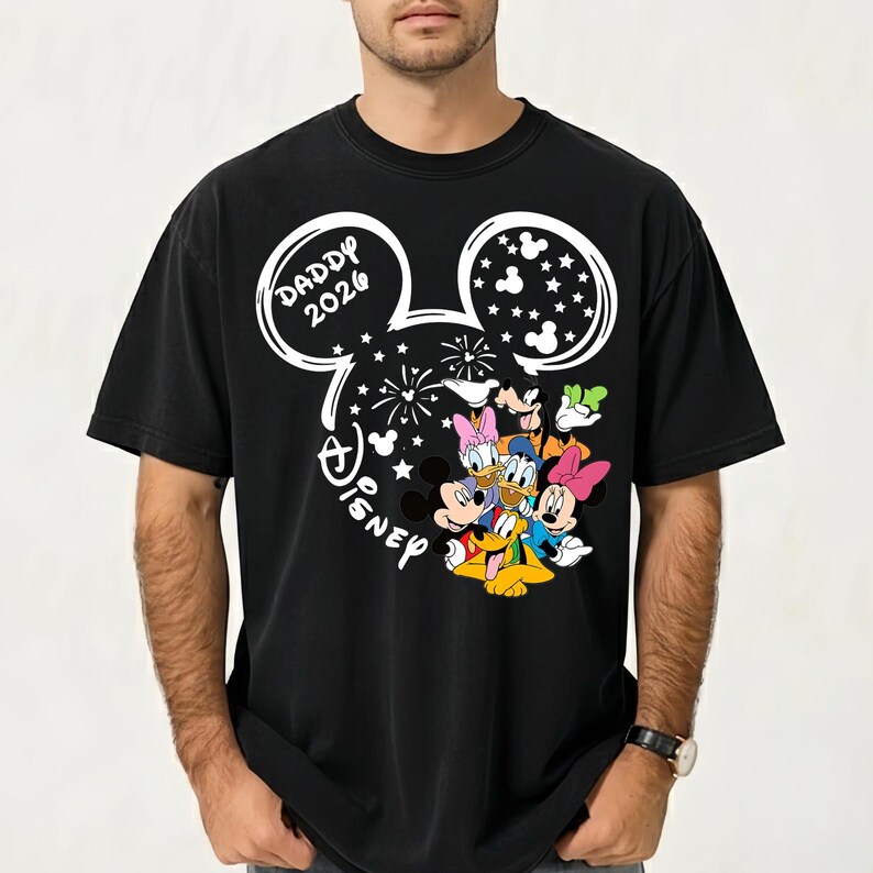 Puede incluir: Camiseta negra con un dise&ntilde;o blanco de la cabeza de Mickey Mouse, el texto "DADDY 2026" y la palabra "Disney". El dise&ntilde;o incluye im&aacute;genes de Mickey, Minnie, Donald, Daisy y Goofy.