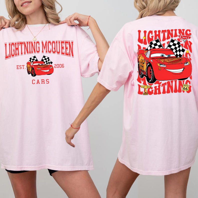 Pode incluir: T-shirts rosa claro com Lightning McQueen do filme Carros. A frente da camisa tem o texto "Lightning McQueen" e um gr&aacute;fico do carro. A parte de tr&aacute;s da camisa tem um gr&aacute;fico maior de Lightning McQueen com bandeiras quadriculadas.