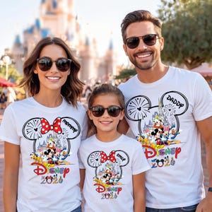 May include: Three white t-shirts featuring a graphic of Mickey Mouse and friends in front of a castle inside a Mickey ear silhouette. The shirts include the text Disney 2020 and personalized names like Mommy, Daddy, and Emily with red bows.