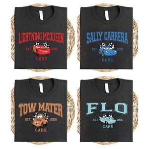 Pode incluir: Quatro camisetas cinza escuro com diferentes designs de personagens do filme Carros. Cada camisa apresenta o nome de um personagem, um gr&aacute;fico de carro, o texto "EST. 2006" e a palavra "CARS". Os designs incluem Rel&acirc;mpago McQueen, Sally Carrera, Mate e Flo.