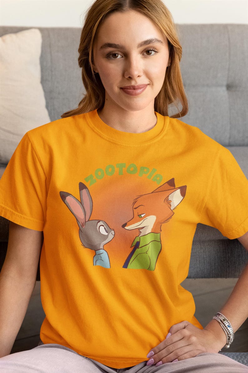 May include: A yellow t-shirt featuring a graphic of Judy Hopps and Nick Wilde from the film Zootopia. The text "Zootopia" is printed in green above the characters.