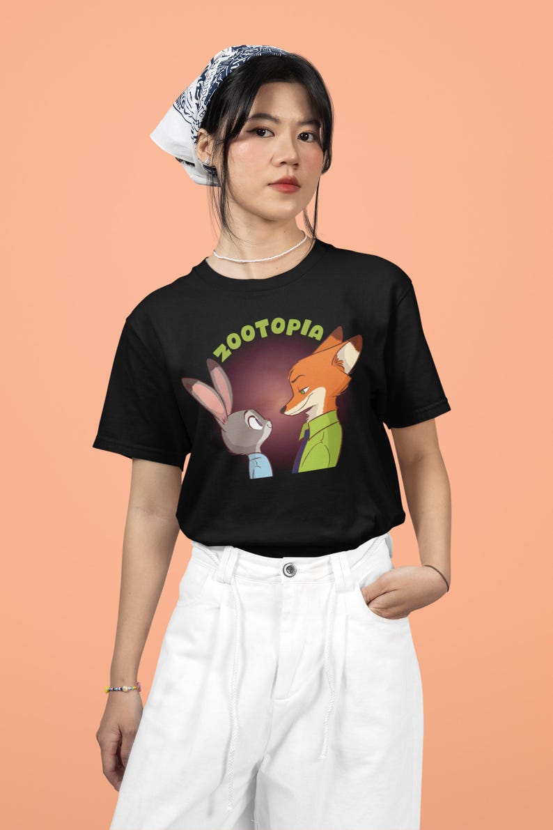 May include: A black t-shirt featuring a graphic of Judy Hopps and Nick Wilde from the film Zootopia. The text "Zootopia" is written in green letters above the characters.