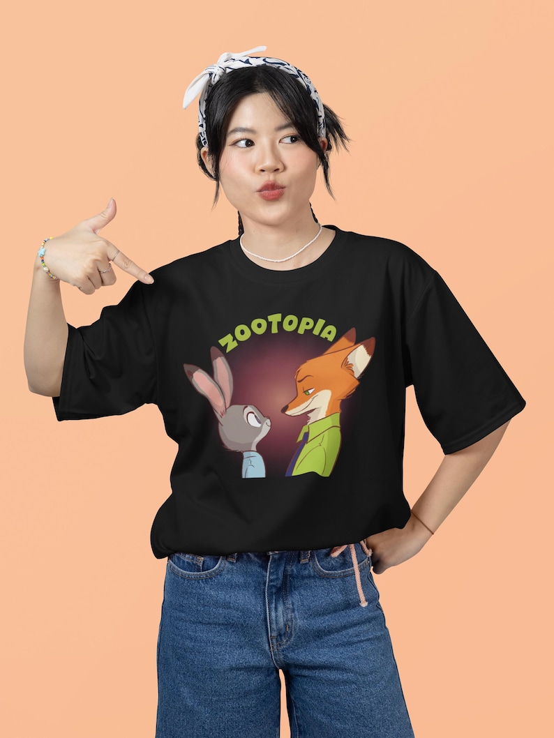 May include: A black t-shirt featuring a graphic of Judy Hopps and Nick Wilde from the film Zootopia. The text "Zootopia" is printed in green letters above the characters.