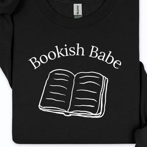 May include: Black sweatshirt with the words "Bookish Babe" in white script above a white line drawing of an open book. The sweatshirt is a heavy blend.