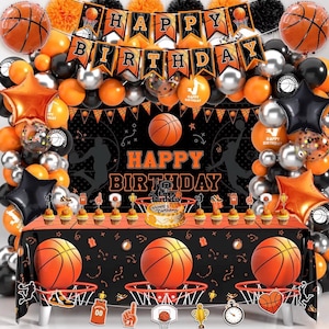 May include: Basketball-themed birthday party decorations. Features a "Happy Birthday" banner, balloons, a table cover with basketballs and hoops, and a cake. The colour scheme is orange, black, and silver.