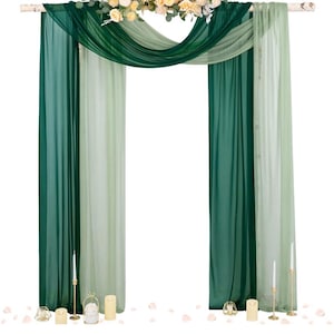 May include: A wedding arch featuring green and white draped fabric, decorated with a floral arrangement of yellow and white flowers. The arch is decorated with candles and rose petals.