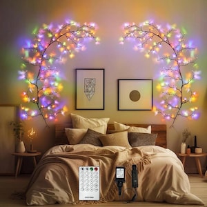 Könnte beinhalten: Ein Schlafzimmer mit einem Bett, das mit einer beigen Bettdecke und Kissen bedeckt ist. Zwei dekorative Zweiglichter mit mehrfarbigen LEDs schmücken die Wand über dem Bett. Eine Fernbedienung und Netzadapter sind ebenfalls sichtbar.