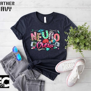 a navy blue t-shirt with a colorful graphic design, a pair of jeans, a pair of sunglasses, a potted plant, and a pair of white sneakers, all laid out on a white background.