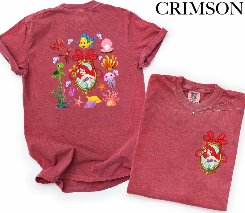 a red t-shirt with a mermaid design and various marine-themed illustrations, including a mermaid, fish, and coral.