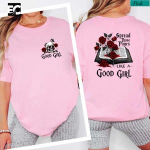 A woman wearing a pink t-shirt with a skull and rose design, and text that says "spread those pages like a good girl".