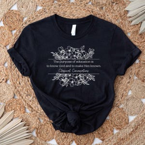 May include: Black t-shirt with a white floral design and the text "The purpose of education is to know God and to make Him known. Classical Conversations."