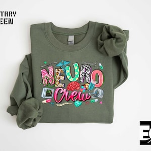 a green sweatshirt with a colorful graphic design on it, including the text "NEURO CREW" and various medical and science-related icons.