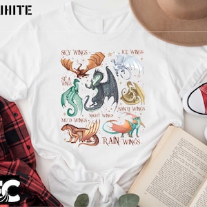 May include: White t-shirt featuring a colorful illustration of various dragon types, each labeled with a unique name such as "Sky Wings" and "Rain Wings". The word "WHITE" is printed at the top left.