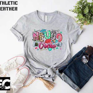 a gray t-shirt with a colorful graphic design, a pair of white sneakers, a pair of sunglasses, and a potted plant.