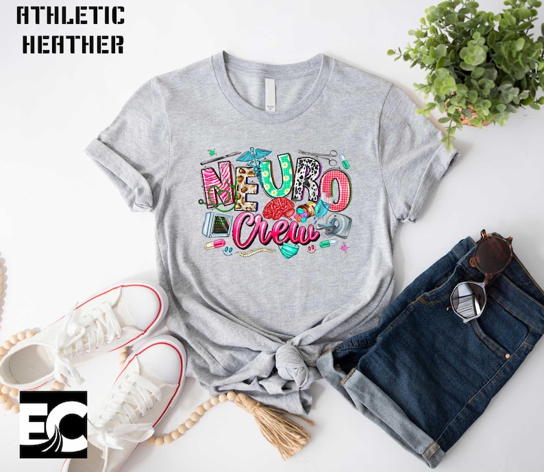 a gray t-shirt with a colorful graphic design, a pair of white sneakers, a pair of sunglasses, and a potted plant.