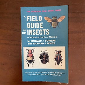 May include: A paperback book titled A Field Guide to the Insects of America North of Mexico by Donald J. Borror and Richard E. White. The blue cover features a large bee illustration at the top and three smaller beetle illustrations at the bottom.