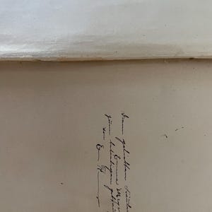 May include: A cream-colored paper surface featuring a handwritten inscription in black ink. The cursive text reads: "Dem geliebten Freunde Emma Meyer zur beliebigen Gedenkung von E. G.". The paper has a smooth texture with a visible horizontal fold line.