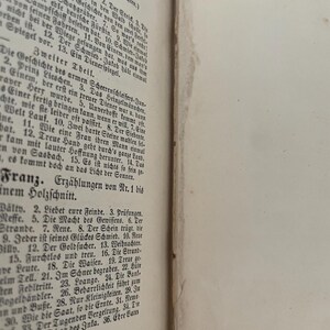 May include: An open antique book with cream-colored pages featuring black printed German text. The left page displays a table of contents organized into sections titled Erster Theil, Zweiter Theil, and Franz, listing numbered stories and titles.