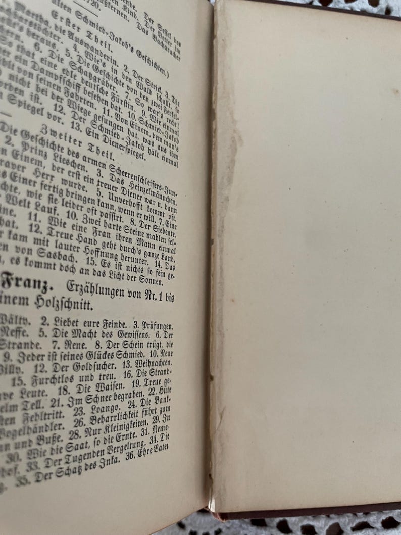 May include: An open antique book with cream-colored pages featuring black printed German text. The left page displays a table of contents organized into sections titled Erster Theil, Zweiter Theil, and Franz, listing numbered stories and titles.