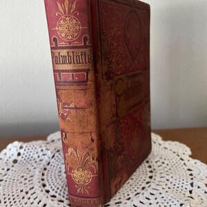May include: A red hardcover book titled Palmbl&auml;tter with gold embossed floral and geometric patterns on the spine and front cover. The spine features the name L. KOHLER at the bottom. The book has a worn texture and stands upright.