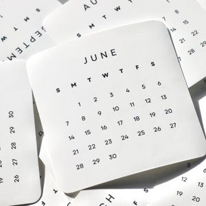 May include: A collection of white square calendar cards with rounded corners, featuring black sans-serif text. The central card displays the month of June with days of the week abbreviated as S M T W T F S and dates numbered 1 through 30 in a grid.