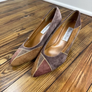 Peut inclure: Une paire d'escarpins vintage Madeline Stuart. Les chaussures présentent un bout pointu avec un motif patchwork dans les tons marron et bordeaux. Les talons sont de couleur marron clair, avec une bordure dorée.