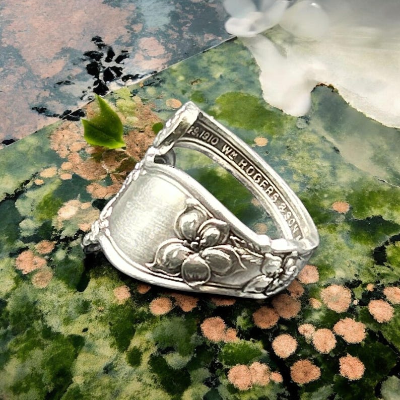 May include: A silver spoon ring with a floral design. The spoon is engraved with "1810 W. ROGERS & SON".