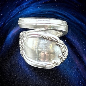 May include: A silver spoon ring, crafted from a vintage spoon, with a twisted design. The ring is made from a single spoon, with the bowl of the spoon forming the top of the ring.