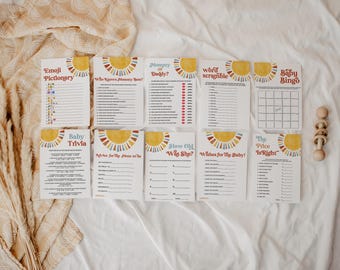 May include: A collection of baby shower game cards with a sunburst design in red, yellow, and orange. Games include "Emoji Pictionary," "Who Knows Mommy Best?" and "Baby Bingo." A wooden toy is also included.