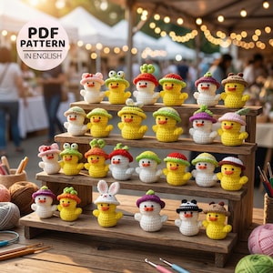 May include: A wooden display shelf holds an assortment of crocheted ducklings and snowmen, each adorned with unique hats. The ducklings are yellow, and the snowmen are white. The text "PDF PATTERN IN ENGLISH" is visible in the upper left corner.