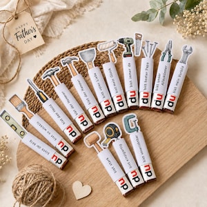May include: A collection of decorative tools with the text "Happy Father's Day" on a tag. The tools include a hammer, screwdriver, level, and more. Each tool has a white label with German text and the word "du".
