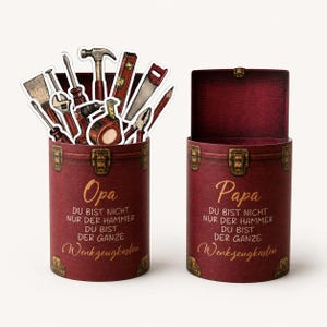 May include: Two burgundy-colored, cylindrical gift boxes with gold-colored hardware. One box is open, and the other contains paper cutouts of tools. The text "Opa" and "Papa" are written on the boxes, along with German text.