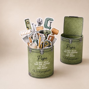 May include: Two olive green toolboxes, one open and one closed, with the text "Papa" and "Werkzeugkasten". The open toolbox is filled with tool illustrations. The text reads "You are not just the hammer, you are the whole toolbox."