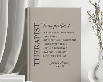 May include: A light beige book with dark gray text. The word THERAPIST is printed vertically on the left. The text reads: In my practice I... FOSTER SAFETY AND TRUST, HOLD SPACE, LISTEN WITHOUT JUDGEMENT, HONOR EVERY STORY, NURTURE RESILIENCE, LEAD WITH HUMILITY, CONTINUE LEARNING. Jessica Nelson, Psy.D. is at the bottom.