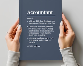 May include: A navy blue notebook with the word "Accountant" in white text at the top. The definition of "Accountant" is listed below the title. The notebook is held by a person.