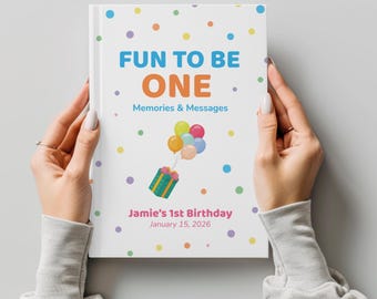 May include: A white memory book with a colorful polka dot pattern. The cover features the text FUN TO BE ONE Memories & Messages, a graphic of a gift box tied to balloons, and the personalized text Jamie's 1st Birthday January 15, 2026.