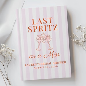 May include: A rectangular book with a light pink and white vertical striped cover. The text reads LAST SPRITZ as a Miss, LAUREN'S BRIDAL SHOWER, and August 20, 2026 in orange. An orange line drawing of two clinking cocktail glasses is centered.