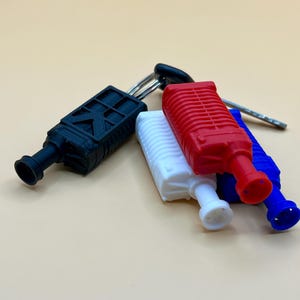 May include: A set of four keychains in black, white, red, and blue. Each keychain has a unique design, with one featuring a geometric pattern. The keychains are attached to a silver key ring.