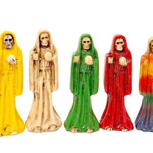 May include: Set of eight small skeletal figures wearing colorful hooded robes. The figures are all in the same pose, with their hands clasped in front of them. The robes are in various colors, including purple, yellow, white, green, red, blue, and pink.