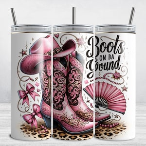 May include: A white tumbler with a pink cowboy hat and boots design. The tumbler has the text "Boots on da Ground" printed on it.
