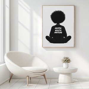 May include: Black and white illustration of a person sitting in a meditative pose with their back to the viewer. The person is wearing a black shirt with the text "Mental Health Matters" printed on the back. The illustration is framed and hanging on a white wall.