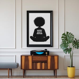 May include: Black and white illustration of a person with an afro sitting in a meditative pose. The person is wearing a black shirt with the text "Mental Health Matters" printed on the back.
