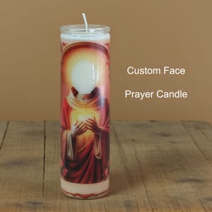 May include: A cylindrical prayer candle with a custom face area. The candle features a religious image in red and gold tones. The text "Custom Face Prayer Candle" is visible on the right side of the candle.