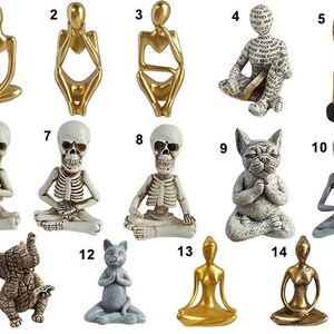 May include: A collection of 14 figurines in various poses, including a skeleton, a cat, an elephant, and an alien. The figurines are made of different materials, including gold, silver, and white.