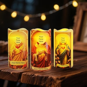Peut inclure: Trois bougies LED sans flamme avec des images religieuses. Chaque bougie présente une figure avec un cœur, un halo et le texte "Your Face Here" et "Your Name Here". Les figures sont vêtues de robes rouges, dorées et vertes, avec des motifs floraux.