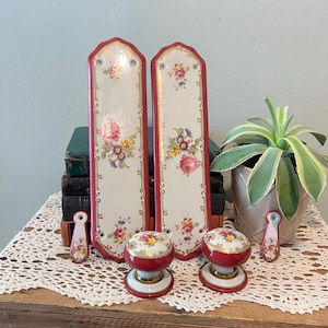 May include: A handmade wooden sign with the text "Welcome" in a playful font. The sign features a distressed white background and a dark stained wooden frame. A decorative floral element is in the corner.