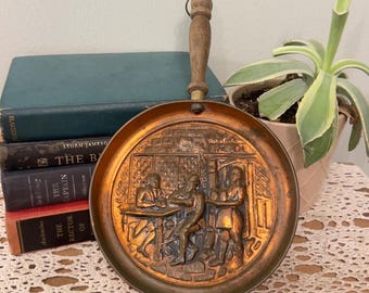 Vintage koperen pan met reliëf en houten handvat