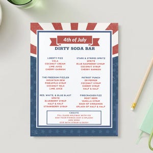 May include: A printed menu for a "Dirty Soda Bar" with a red, white, and blue theme, perfect for a 4th of July celebration. The menu lists various soda concoctions with ingredients like cola, coconut cream, and cherry garnish. A pencil and a green keychain are on the table.