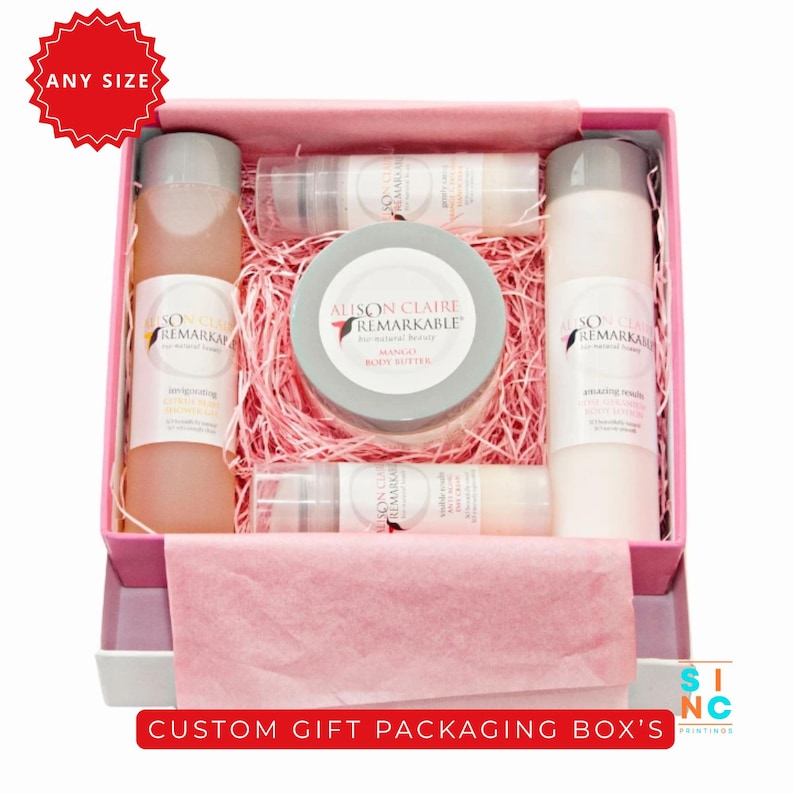 Puede incluir: Una caja de regalo rosa llena de productos de belleza, incluyendo botellas y un tarro de manteca corporal. Los productos est&aacute;n dispuestos sobre papel triturado rosa. La caja tiene el texto "CUSTOM GIFT PACKAGING BOX'S".